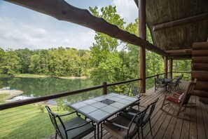 A wooden deck with a table and chairs overlooking a lake, surrounded by trees. - 3 acre Lake, Farm Animals Petting Zoo, Horses and Horseback Riding, Room to roam (Brownsburg)