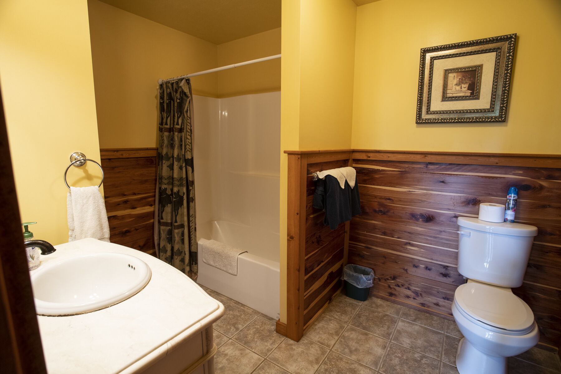 A bathroom with a wooden vanity, a shower, and a toilet.