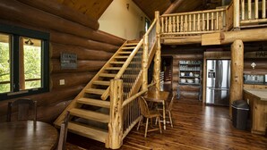 A rustic cabin interior with a wooden staircase, a dining area, and a kitchen with a stainless steel refrigerator. - 3 acre Lake, Farm Animals Petting Zoo, Horses and Horseback Riding, Room to roam (Brownsburg)