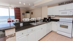 A kitchen with white cabinets, a black countertop, a microwave, and an oven.