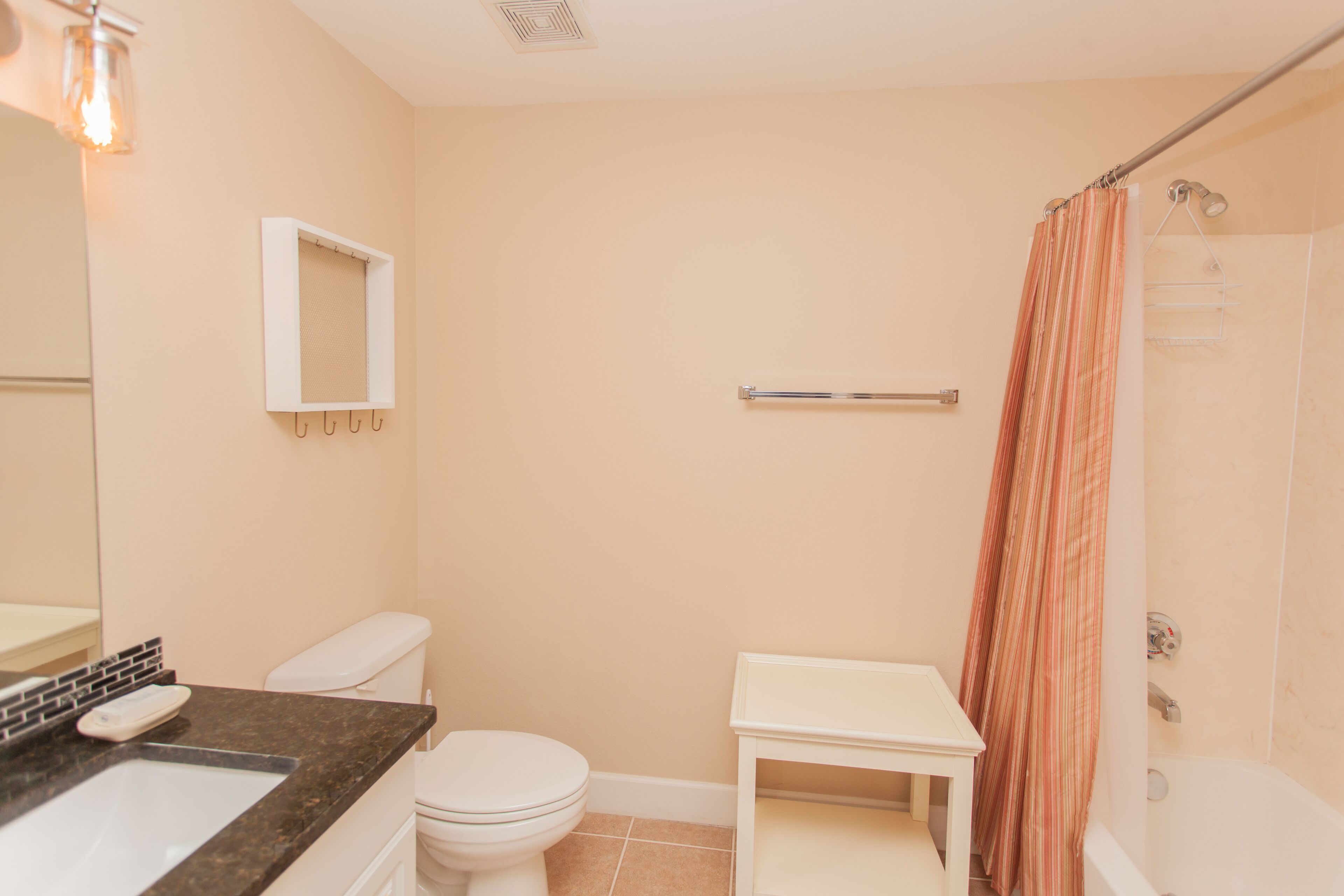 A bathroom with a toilet, sink, mirror, and shower curtain.