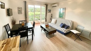 A living room with a dining table, chairs, a sofa, a coffee table, and a chandelier. - Charming Apt On Cote D'azur With Sea Views, Walking Distance To Beach And Shops  (La Croix-Valmer)