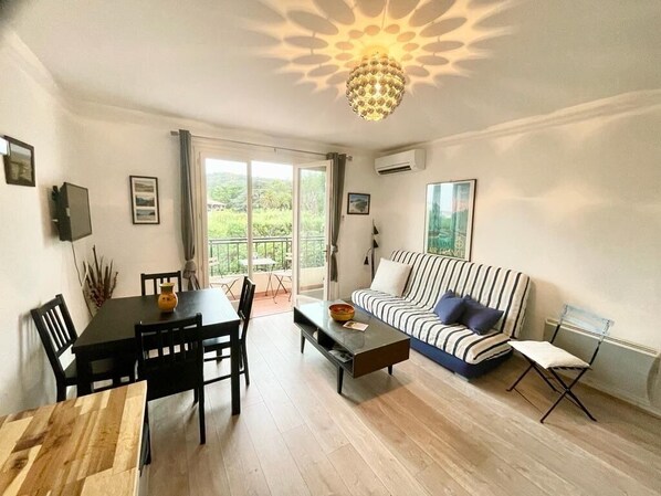 A living room with a dining table, chairs, a sofa, a coffee table, and a chandelier.