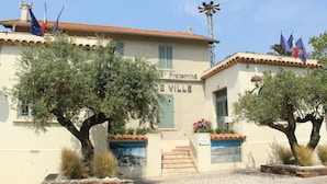 A building with a sign reading "Hotel Fraternité de Ville" and a windmill on the roof. - Charming Apt On Cote D'azur With Sea Views, Walking Distance To Beach And Shops  (La Croix-Valmer)