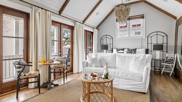 A cozy living room with a white sofa, a round wooden coffee table, and a dining area with a small table and chairs. - Great for Large Groups | The Waltz (Charleston)