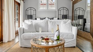 A cozy room with a white sofa, a glass table with a bottle and glasses, and a large mirror reflecting the room. - Great for Large Groups | The Waltz (Charleston)