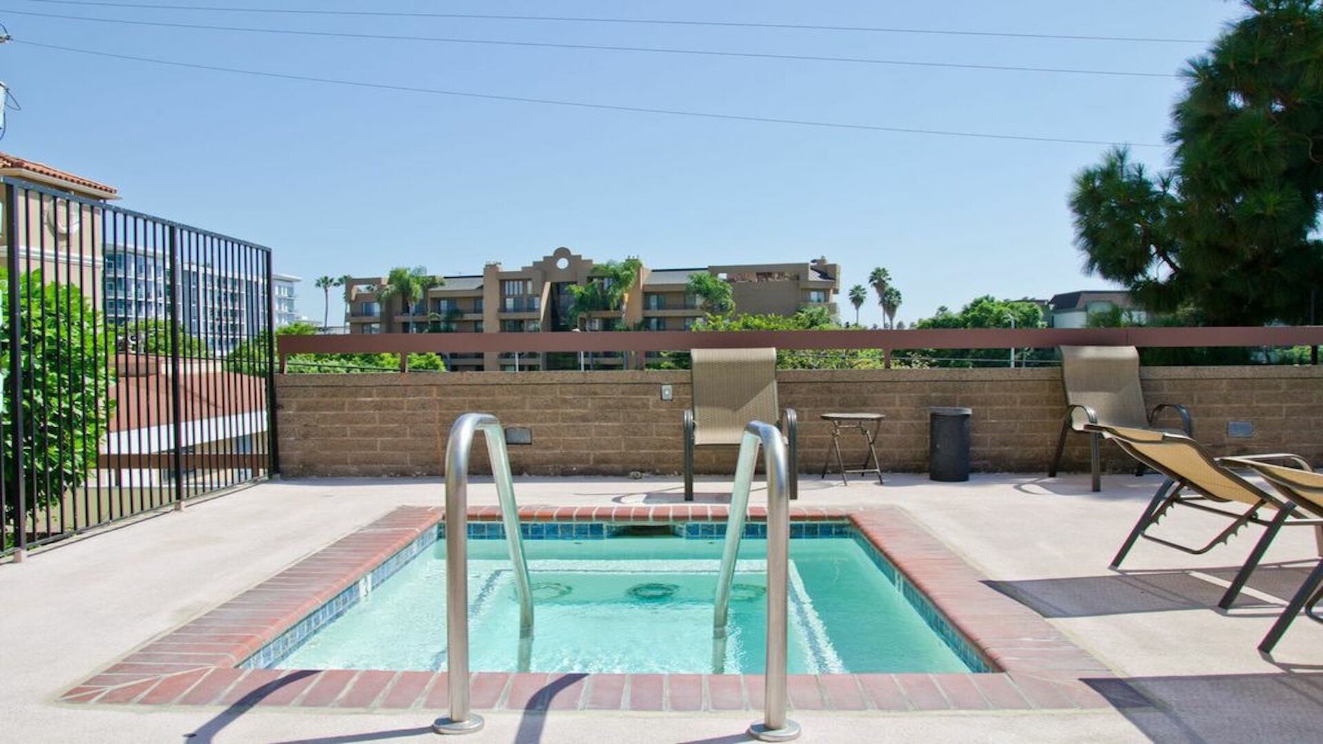 Une piscine équipée de deux échelles, de chaises longues et bordée d’un mur en briques.