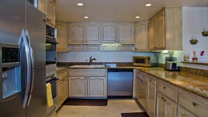 A kitchen with wooden cabinets, a stainless steel refrigerator, a dishwasher, and a microwave.