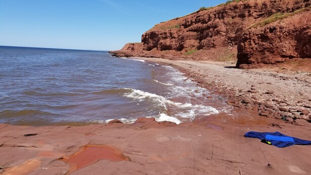 A beach with red rocks and a cliff. - Picturesque oceanfront / beachfront estate, PEI tourism license # 2101170 (Burton)