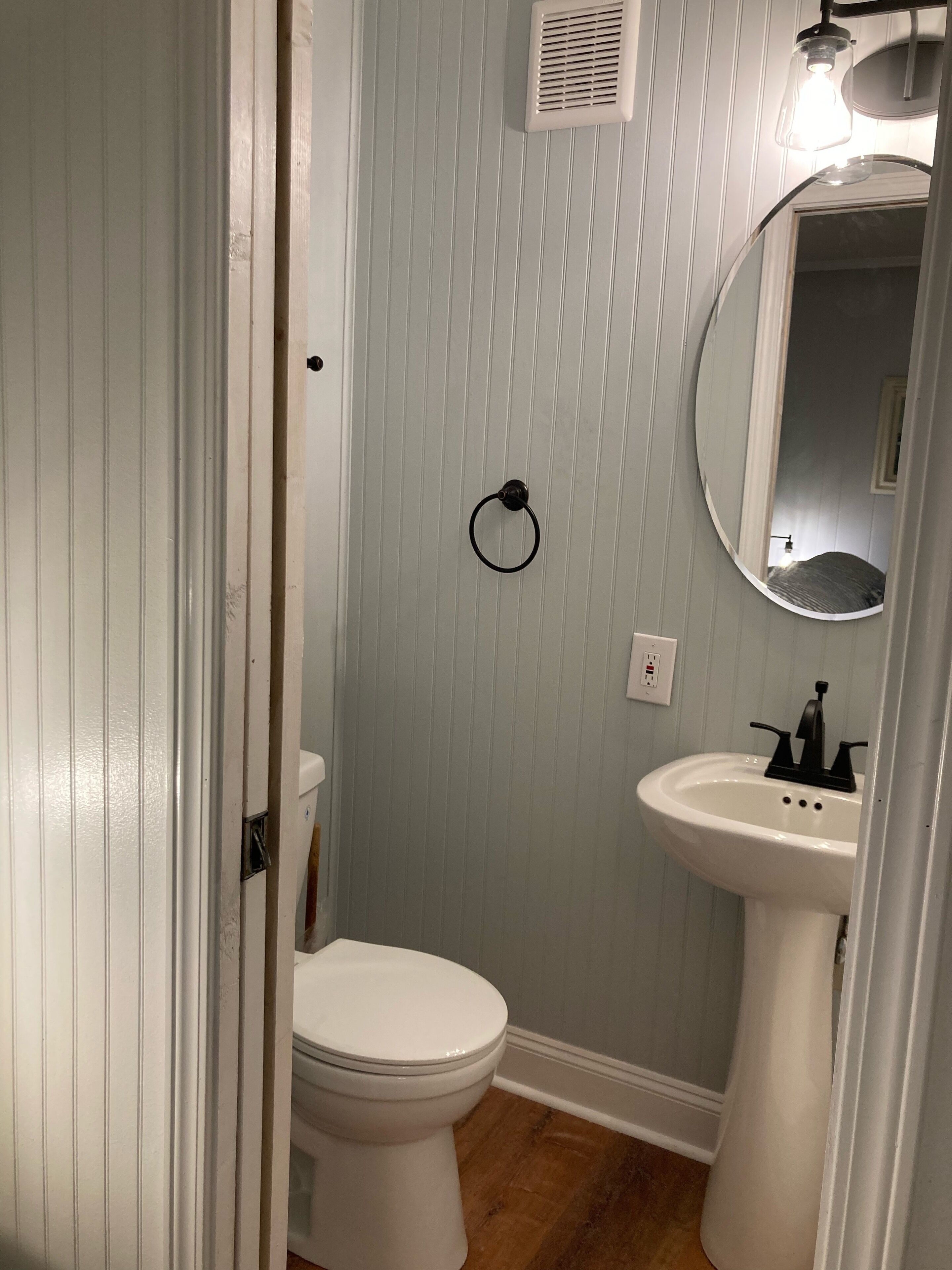 A bathroom with a toilet, sink, and mirror.