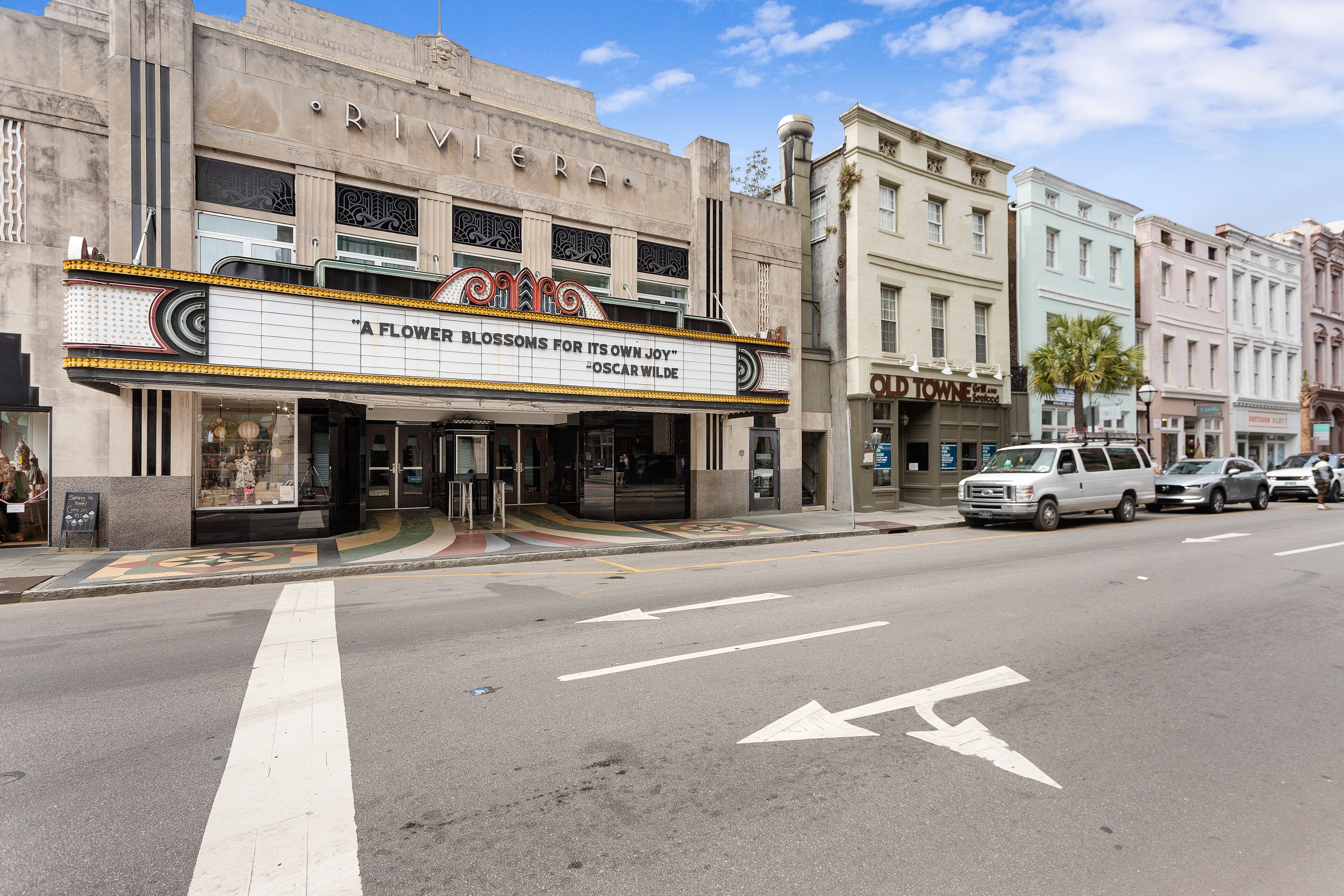 A theater with a marquee advertising 'A Flower Blossoms for Its Own Joy' by Oscar Wilde.