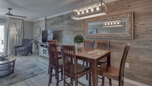 Un'area pranzo con un tavolo e sedie in legno, un lampadario e un grande specchio a parete.