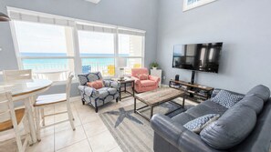A living room with a TV, a sofa, a coffee table, and a dining area with chairs. - BLUE DOLPHIN PENTHOUSE LUXURY 3 BDR 3 BA 2026 Booking Fast (Fort Walton Beach)