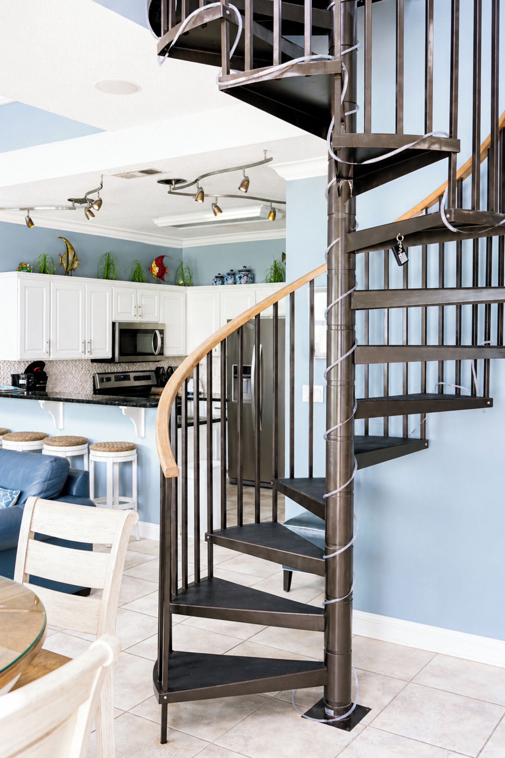 A modern kitchen with white cabinets, a black countertop, and a stainless steel refrigerator.