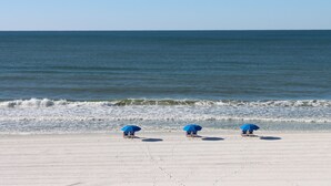 Una spiaggia con tre ombrelloni blu e una vista libera sull'oceano.