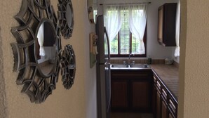 A kitchen with a double sink, wooden cabinets, and a decorative mirror with a unique design. - A charming house surrounded by beautiful nature. Cosy, WiFi & fully equipped. (Nuevo Arenal)