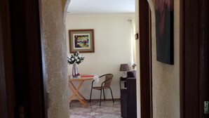 A hallway with a tiled floor, a dining area with a table and chairs, and a painting on the wall. - A charming house surrounded by beautiful nature. Cosy, WiFi & fully equipped. (Nuevo Arenal)