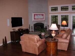 A living room with a fireplace, leather sofas, a television, and a lamp.