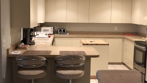 Eine moderne Küche mit einer zentralen Kochinsel, Barhocker, einer Mikrowelle, einem Toaster und einer Kaffeemaschine.