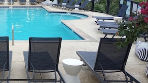 Un espace piscine avec des chaises longues et une petite table.
