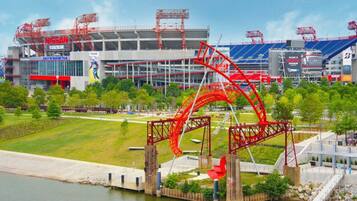 A stadium with a roller coaster, a large scoreboard, and a grassy field.