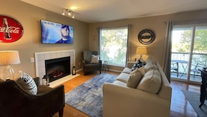 Un salon avec une cheminée, un canapé, une table basse et un téléviseur fixé au mur.