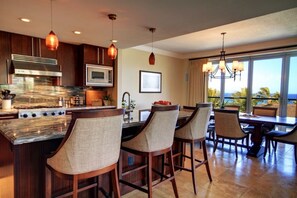 Una cocina moderna con una isla grande, taburetes de bar y un comedor con vistas.