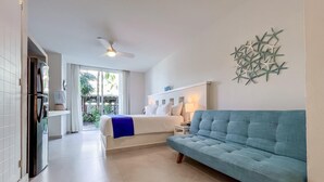 A hotel room with a bed, a blue sofa, a ceiling fan, and a decorative wall piece. - Ixchel Beach Hotel. Steps away from North Beach (Isla Mujeres)