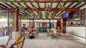 An outdoor café with wooden tables and chairs, a menu board, and hanging plants. - Ixchel Beach Hotel. Steps away from North Beach (Isla Mujeres)