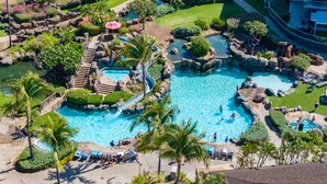 An aerial view of a resort with multiple swimming pools, a waterfall, and a variety of tropical plants.