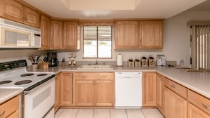 A kitchen with wooden cabinets, a microwave, stove, sink, and dishwasher. - Incredibly Spacious Floorplan with Pool- 3 Bedroom/2 Bath Home (Lake Havasu City)
