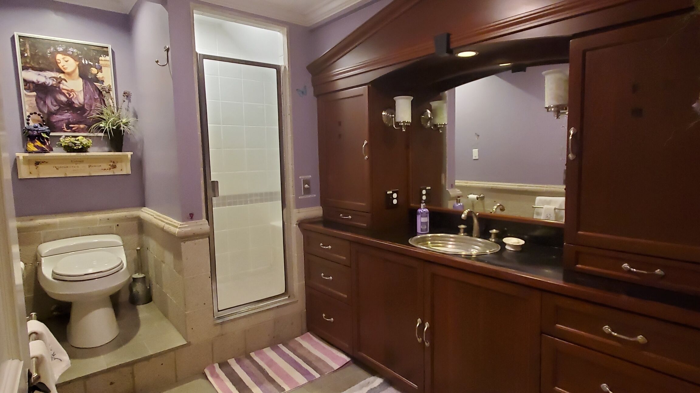 A bathroom with a toilet, a shower, a sink, and a cabinet.