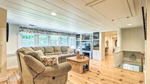 Uma sala de estar espaçosa com um sofá grande, piso de madeira e uma televisão.