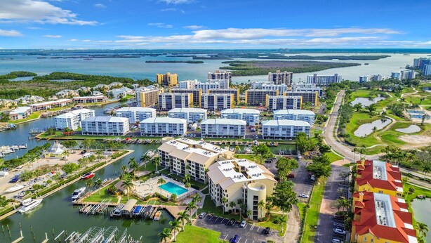 Un complejo hotelero frente al mar con varias edificaciones, un puerto deportivo y una piscina.