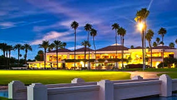A large, well-lit hotel with multiple stories, surrounded by palm trees and a golf course. - Fantastic Mt Views From this Beautiful Mission Hills Country Club Condo (Rancho Mirage)