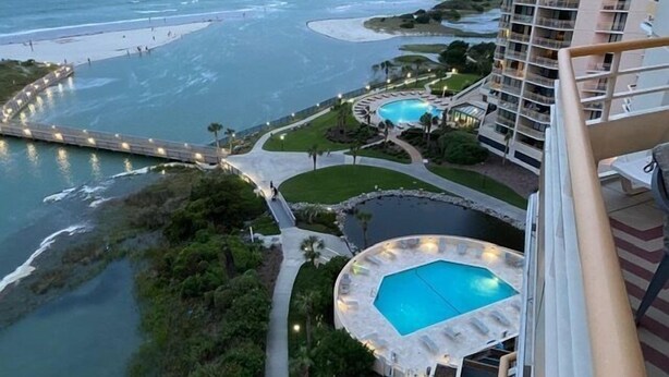 A resort with a large pool, a beach area, and a view of the ocean.