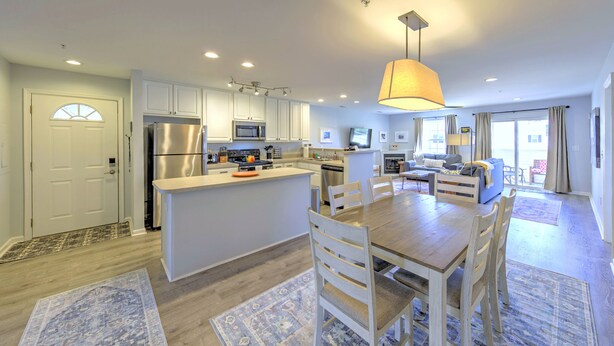 A modern kitchen with a central island, white cabinetry, and stainless steel appliances.