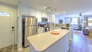 A modern kitchen with stainless steel appliances, a central island, and a dining area with a sofa and coffee table.