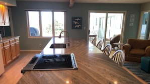 Een moderne keuken met een groot schiereiland, houten kastjes en een eethoek met een tafel en stoelen.