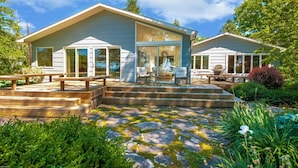 Een modern huis met een overdekt terras, buitenmeubels en een terras van stenen tegels.