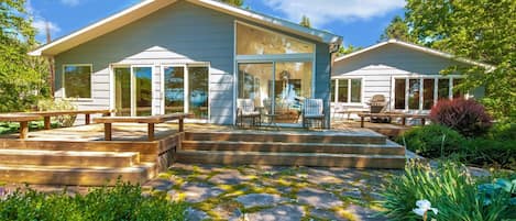 Uma casa moderna com varanda coberta, área de estar externa e um deck com piso de pedra.