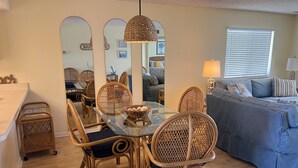 A dining area with a glass table, wicker chairs, and a hanging light fixture. - LOW RATES - Very Clean, Building G, 2/2 Pool, Beach, Tennis, Wifi Top floor (Saint Augustine)