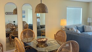 A dining area with a glass table, wicker chairs, and a hanging light fixture. - LOW RATES - Very Clean, Building G, 2/2 Pool, Beach, Tennis, Wifi Top floor (Saint Augustine)