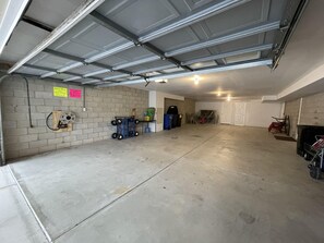 Garage with a brick wall, metal door, and storage space.