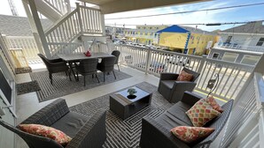 Een balkon met rieten meubilair, een eettafel en uitzicht op de stad.