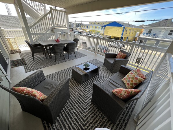 A balcony with wicker furniture, a dining table, and a view of the cityscape. - Beautiful FAMILY Condo Steps From Beach & Boardwalk. No prom/graduation parties. (Wildwood)