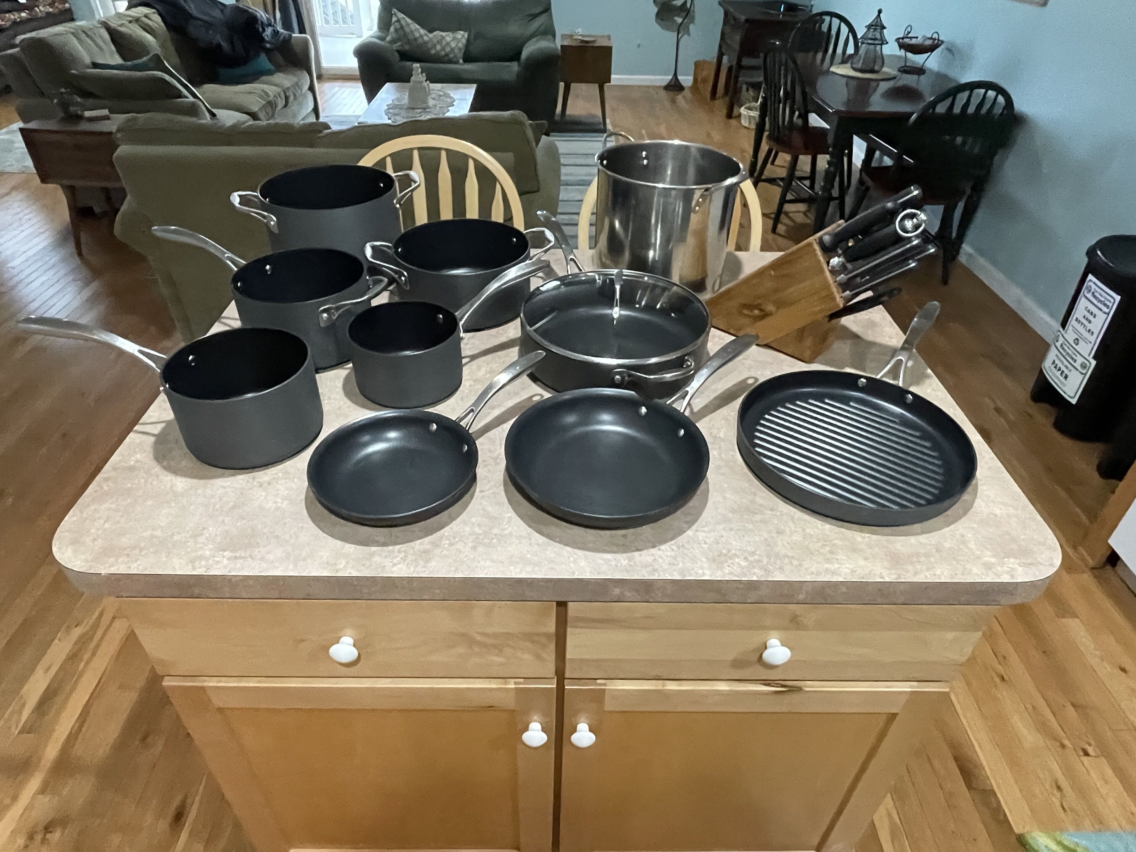 A kitchen counter with various cookware, including pots, pans, and a grill pan.