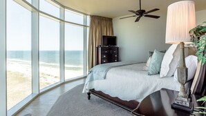 Un dormitorio con techo curvo, cama, televisor, lámpara y vista a la playa.
