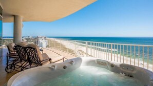 Un balcón con jacuzzi, sillones de descanso y vista al océano.