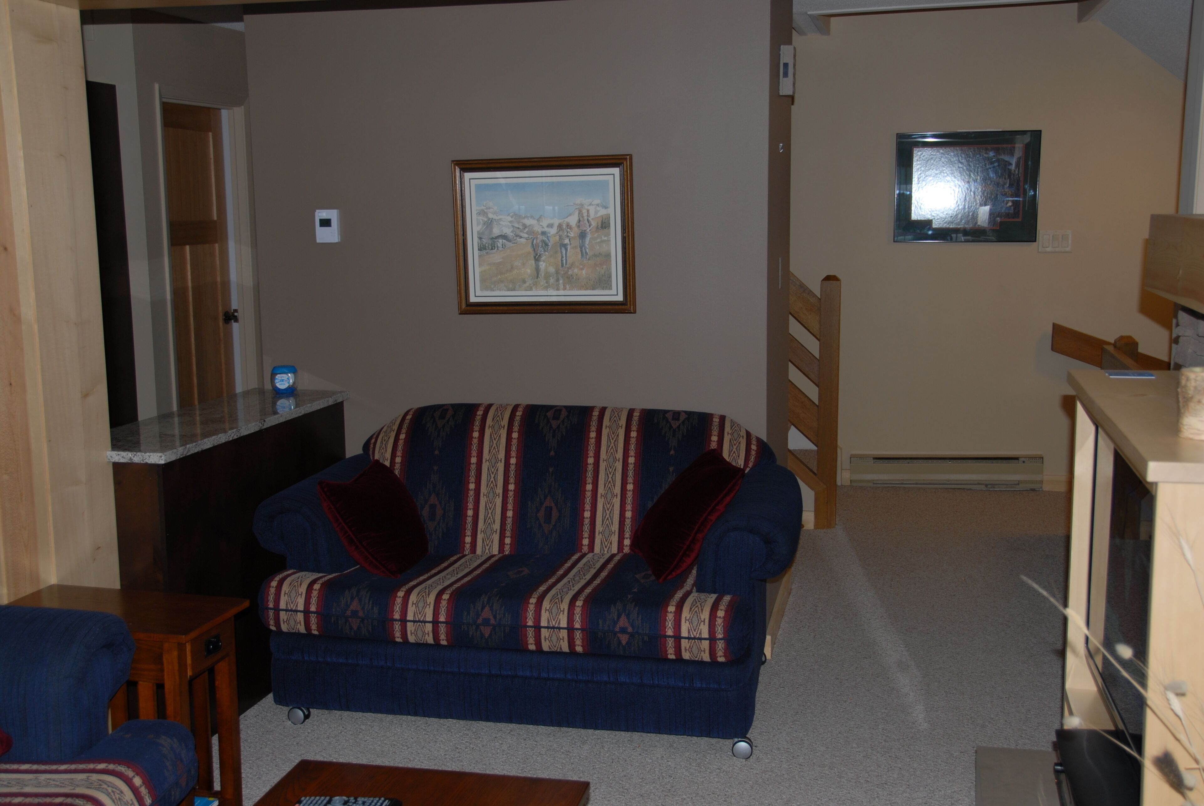 A living room with a patterned sofa, a small table, and a painting on the wall.